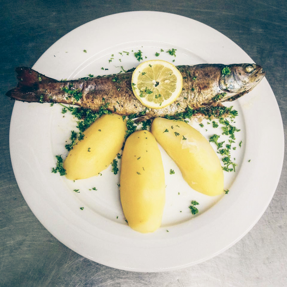 Teller mit ganzem gebratenen Fisch und Kartoffeln