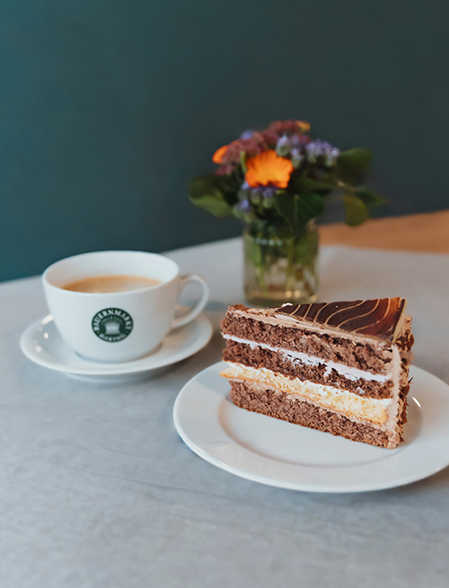 Tortenstück, Tasse, Blumen auf Tisch